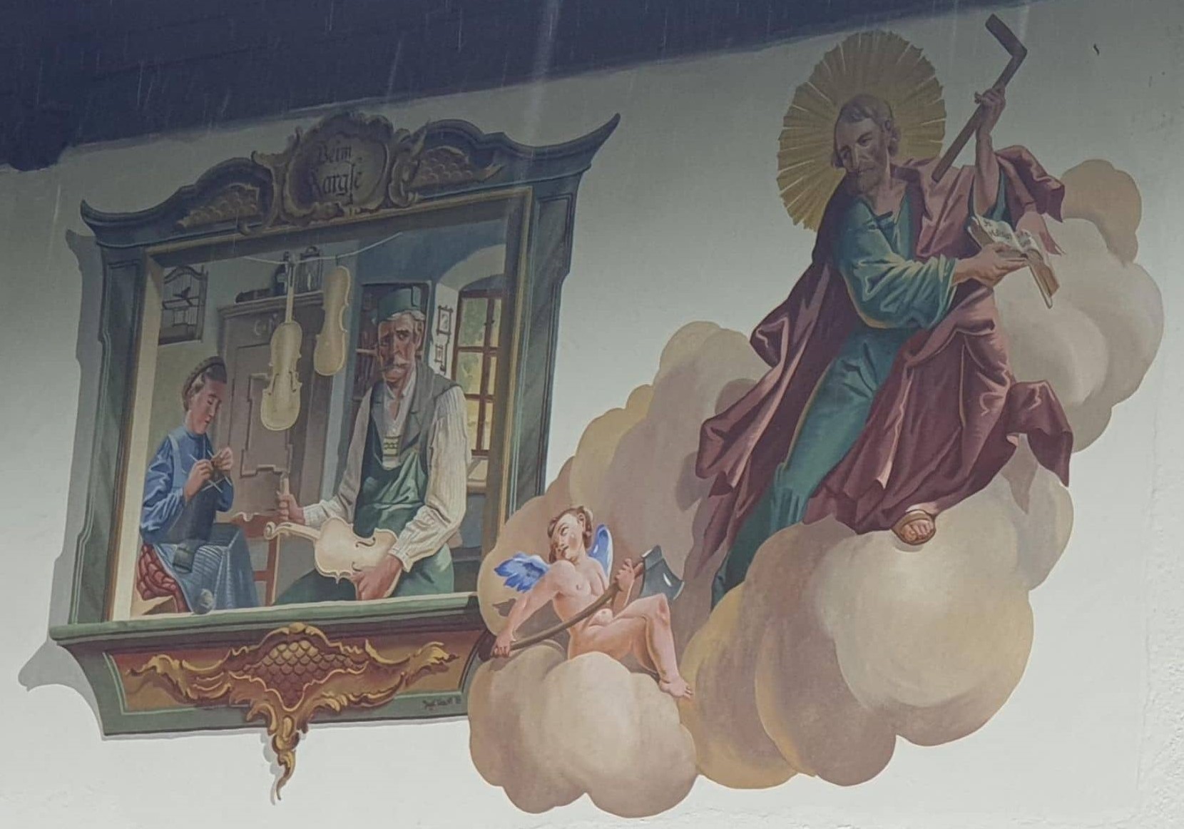 Painting on a guesthouse shows Mathias Klotz crafting a violin while his wife knits a muffler. Mr. Klotz looks out of the window and sees God with an angel.